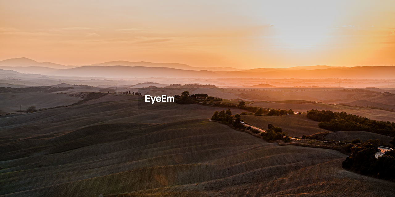 Scenic view of agricultural field against sky during sunset