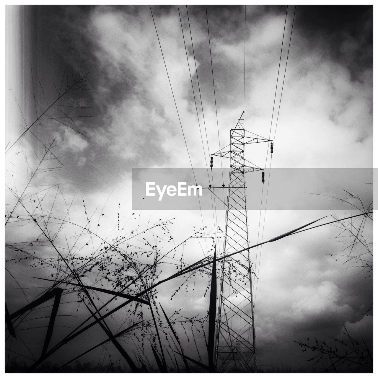 Low angle view of electricity pylon against cloudy sky