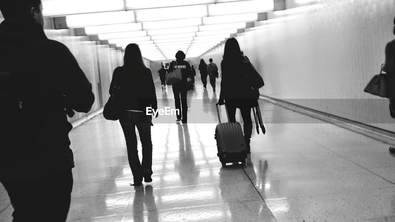 People walking with luggage on tiled flooring