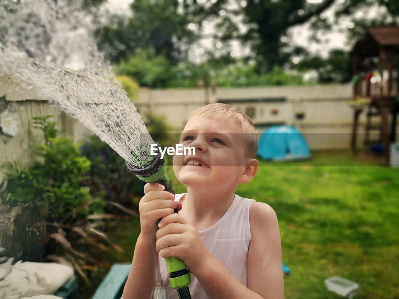 Cute boy spraying water at back yard