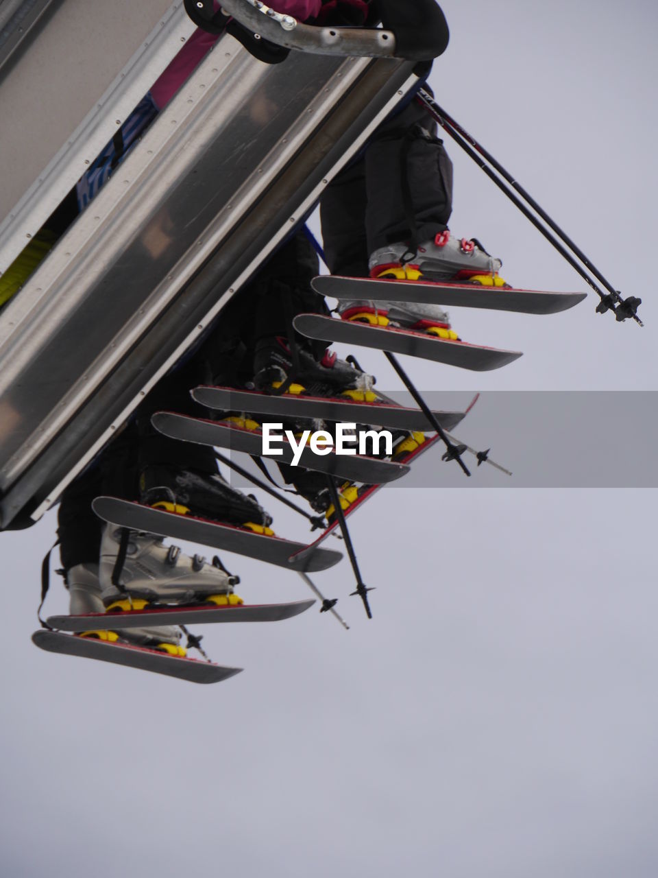 Low angle view of skiers sitting on ski lift