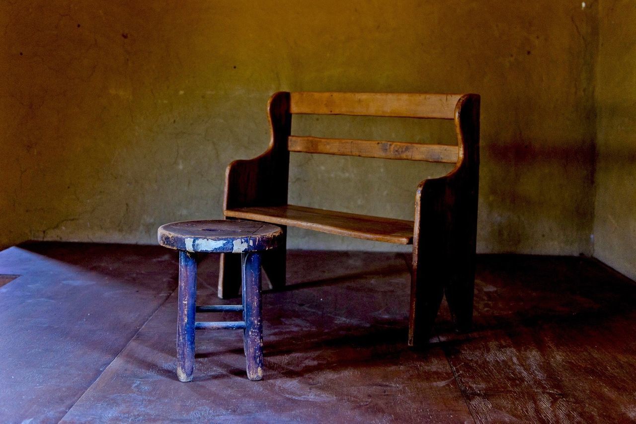 Wooden seat and table against wall in room