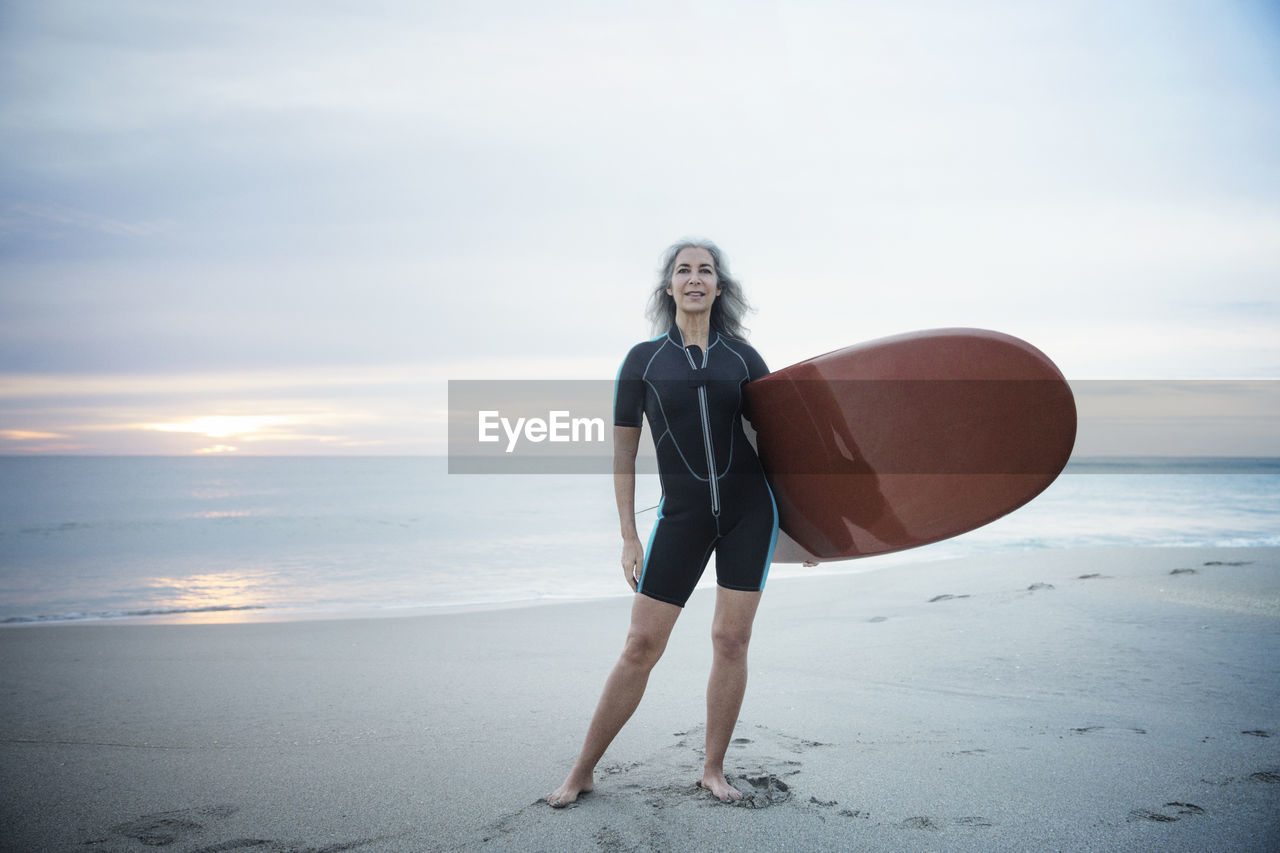 Full length portrait of confident female surfer carrying surfboard at delray beach