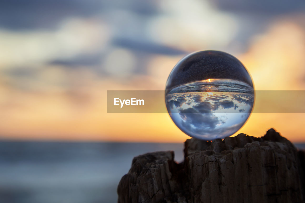 CLOSE-UP OF CRYSTAL BALL ON ROCK AGAINST SEA