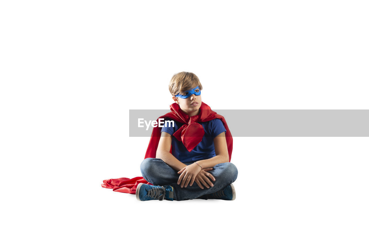 FULL LENGTH PORTRAIT OF BOY SITTING ON WHITE BACKGROUND