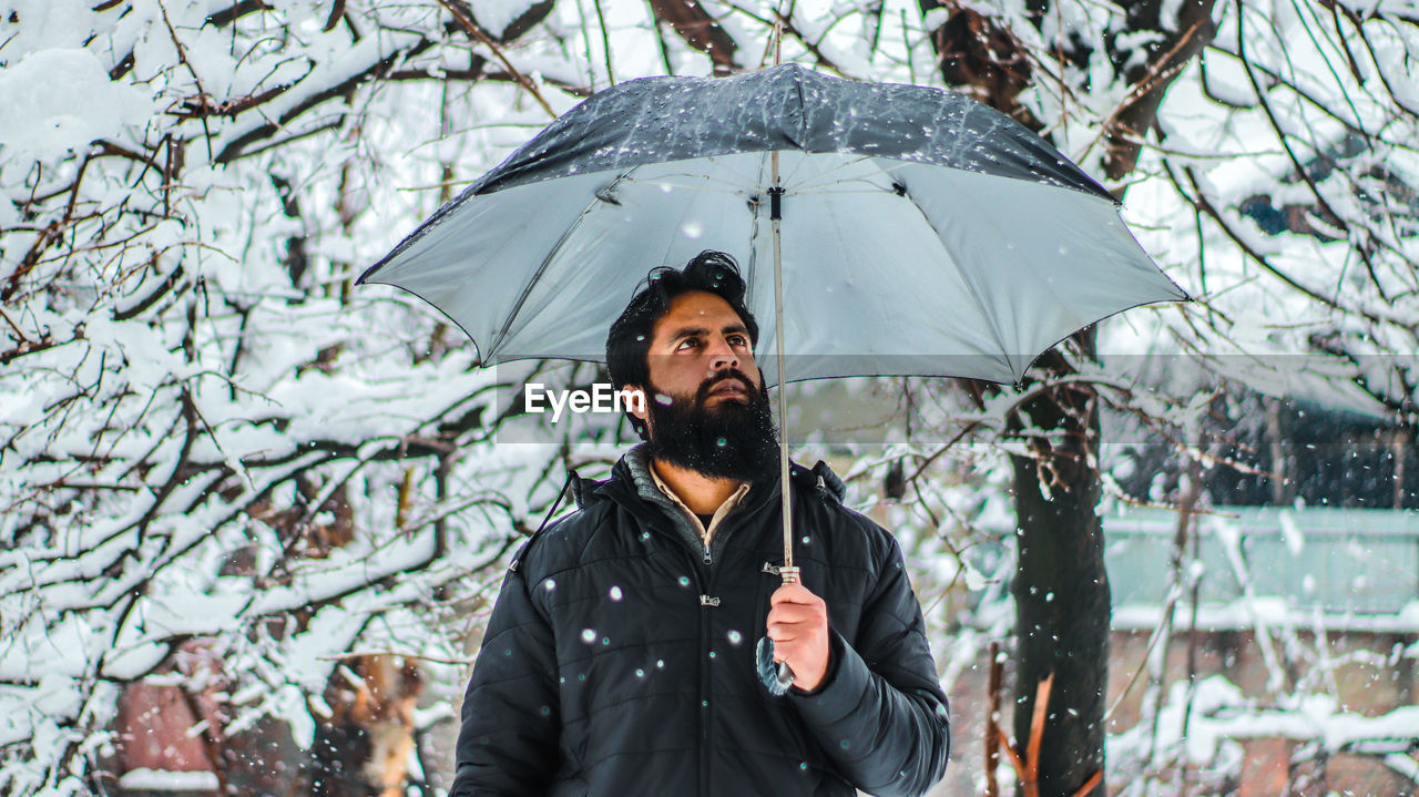 Young man holding umbrella during winter