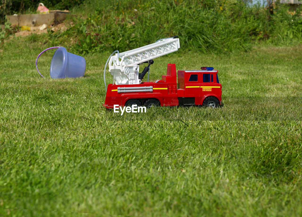 Fire rescue toy car in green grass field.
red tractor on field.
