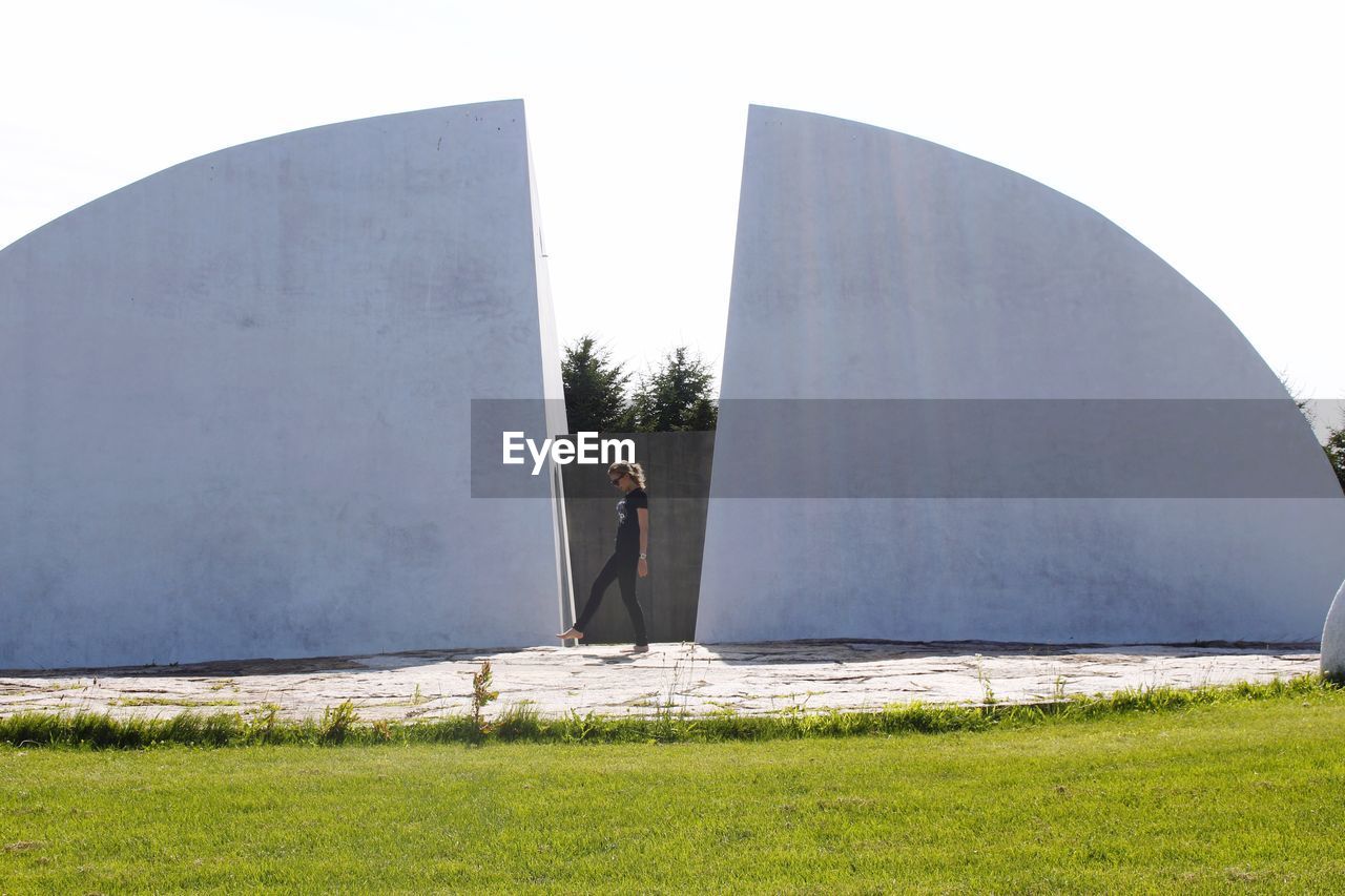 MAN STANDING BY FIELD AGAINST CLEAR SKY