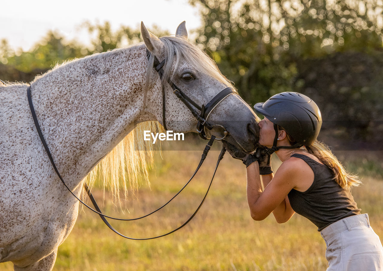 Lusitano mare, female dressage rider, giving horse a kiss on the nose.