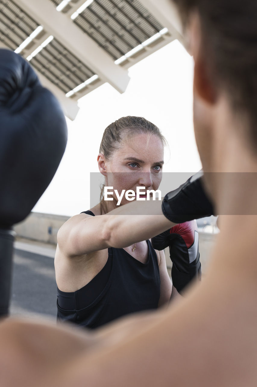 Female athlete with male instructor practicing boxing