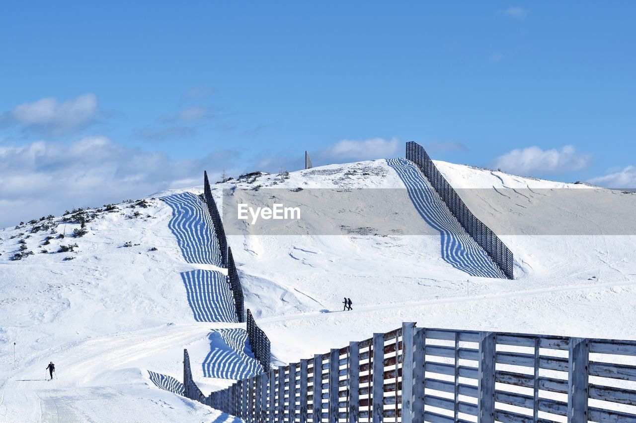 People on snow covered mountain against blue sky