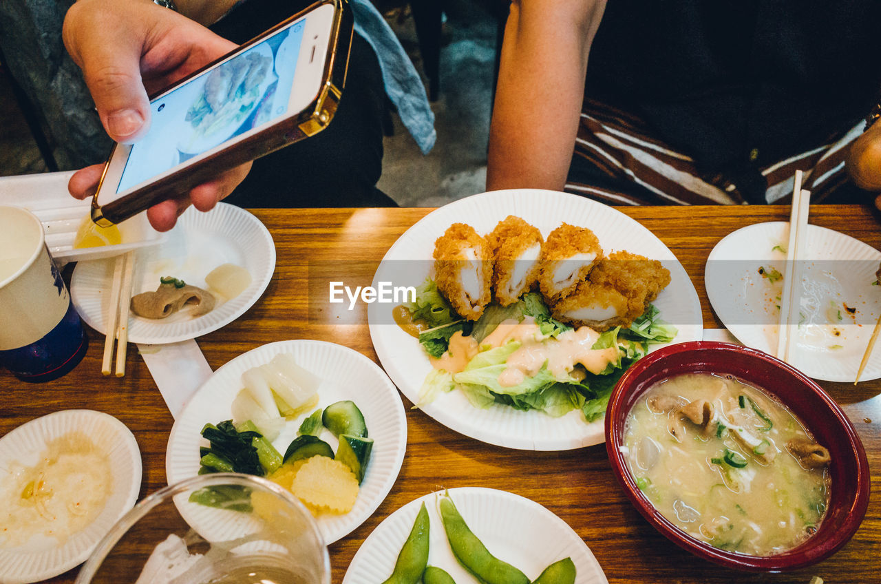 Cropped hand photographing food served at table