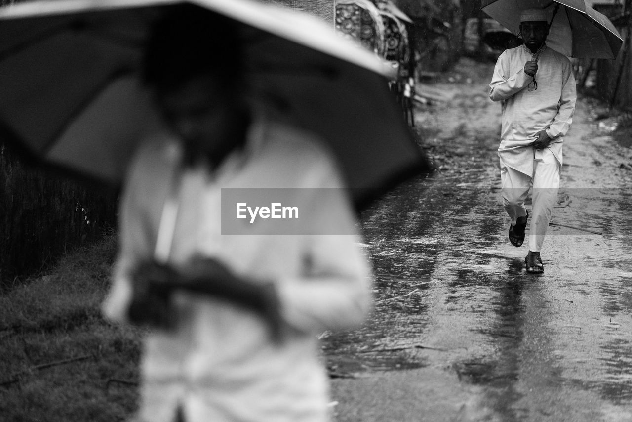 PEOPLE WALKING ON WET STREET IN CITY