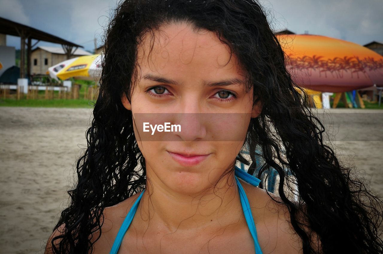 Close-up portrait of young woman standing at beach