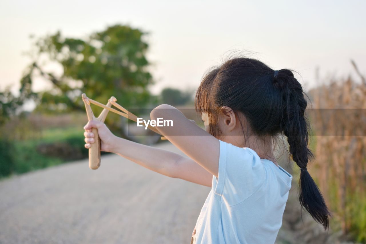 Rear view of girl playing with toy against sky