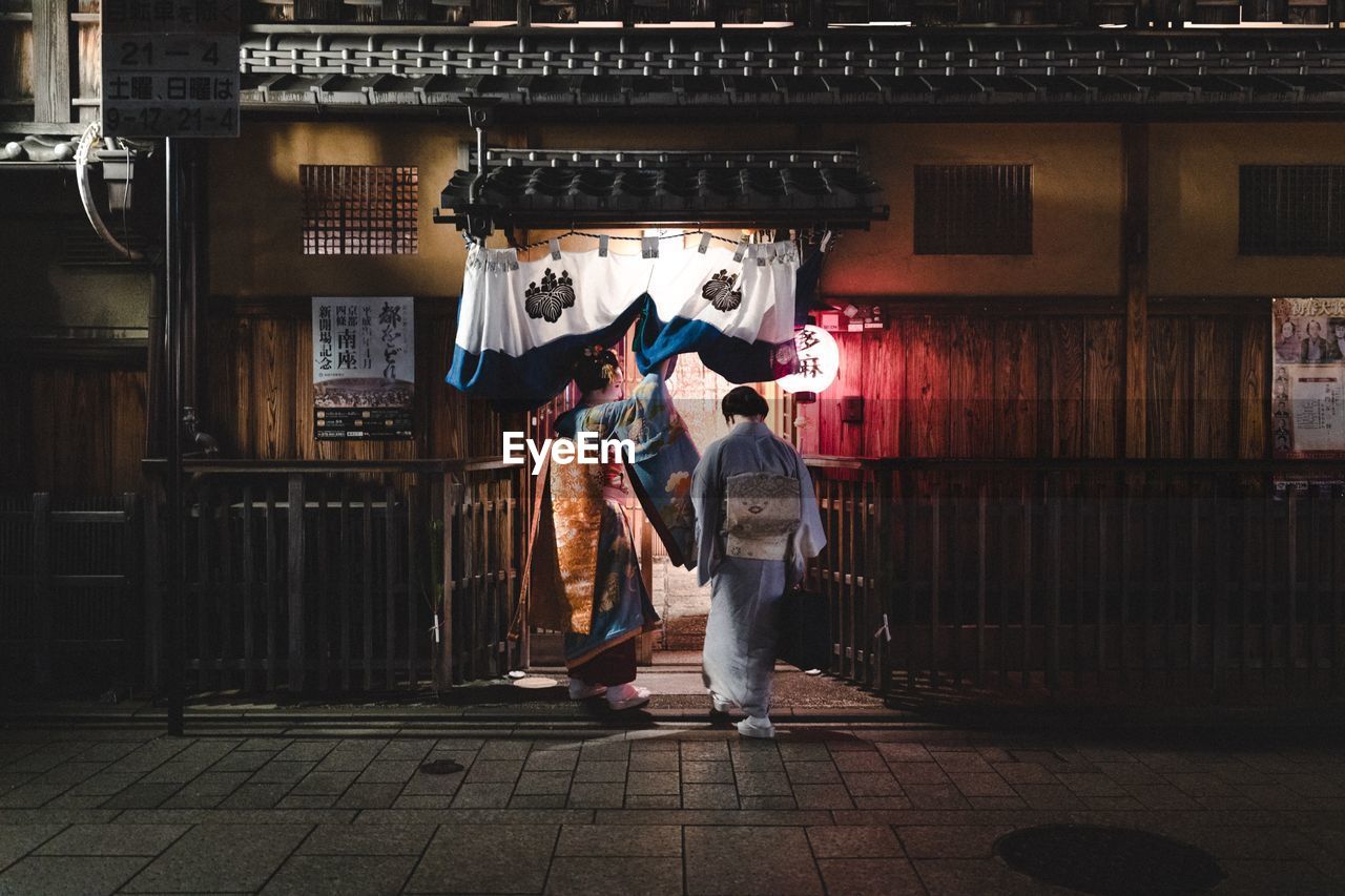 FULL LENGTH OF FRIENDS STANDING ON STREET AGAINST BUILDING