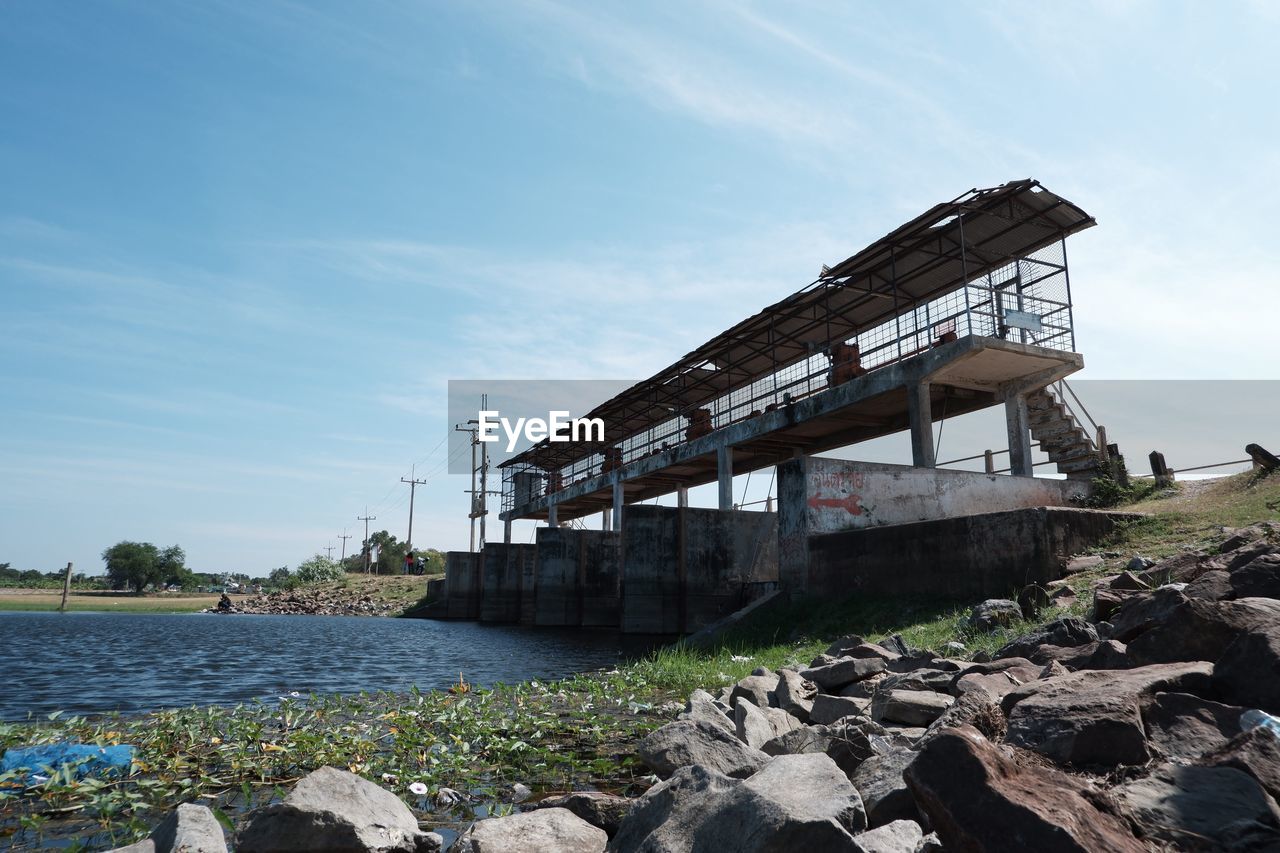 View of abandoned bridge over river against sky