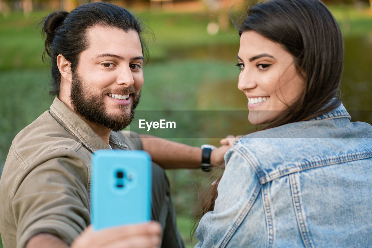 Smiling couple taking selfie at park