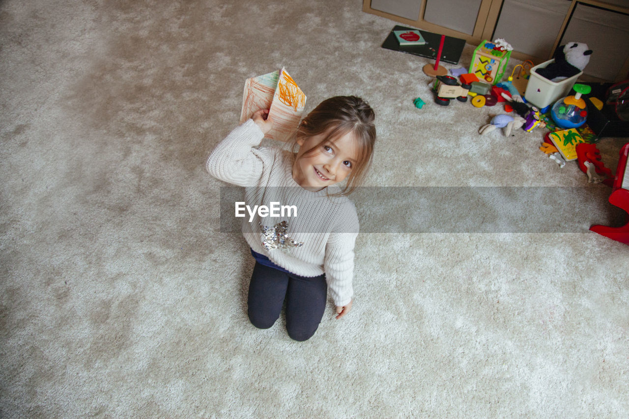 High angle portrait of girl playing with paper airplane 