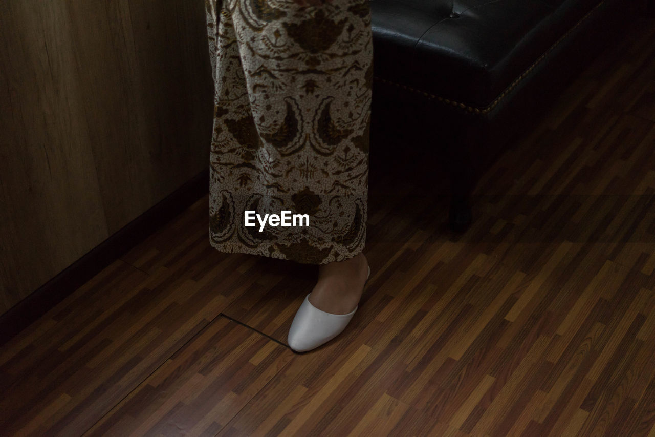 Low section of woman standing on wooden floor