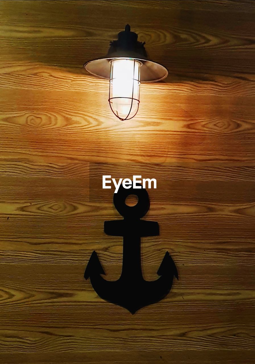 Illuminated light bulb on wooden wall