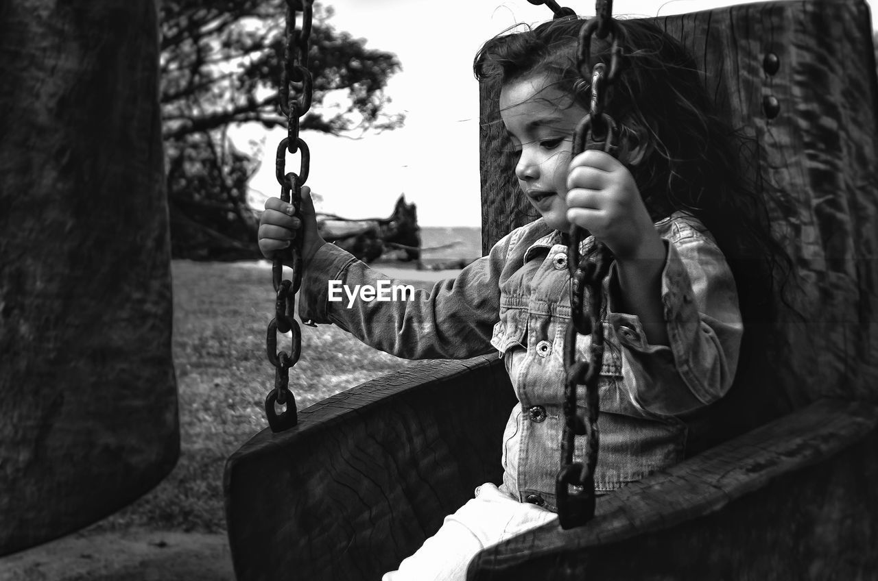 Girl sitting on swing in playground