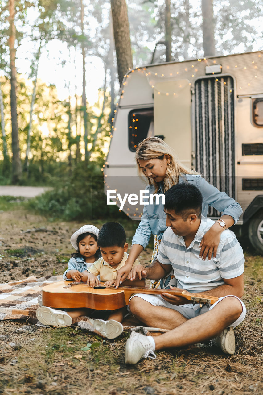 An asian family is vacationing traveling on a road trip by a camper car in the forest in nature