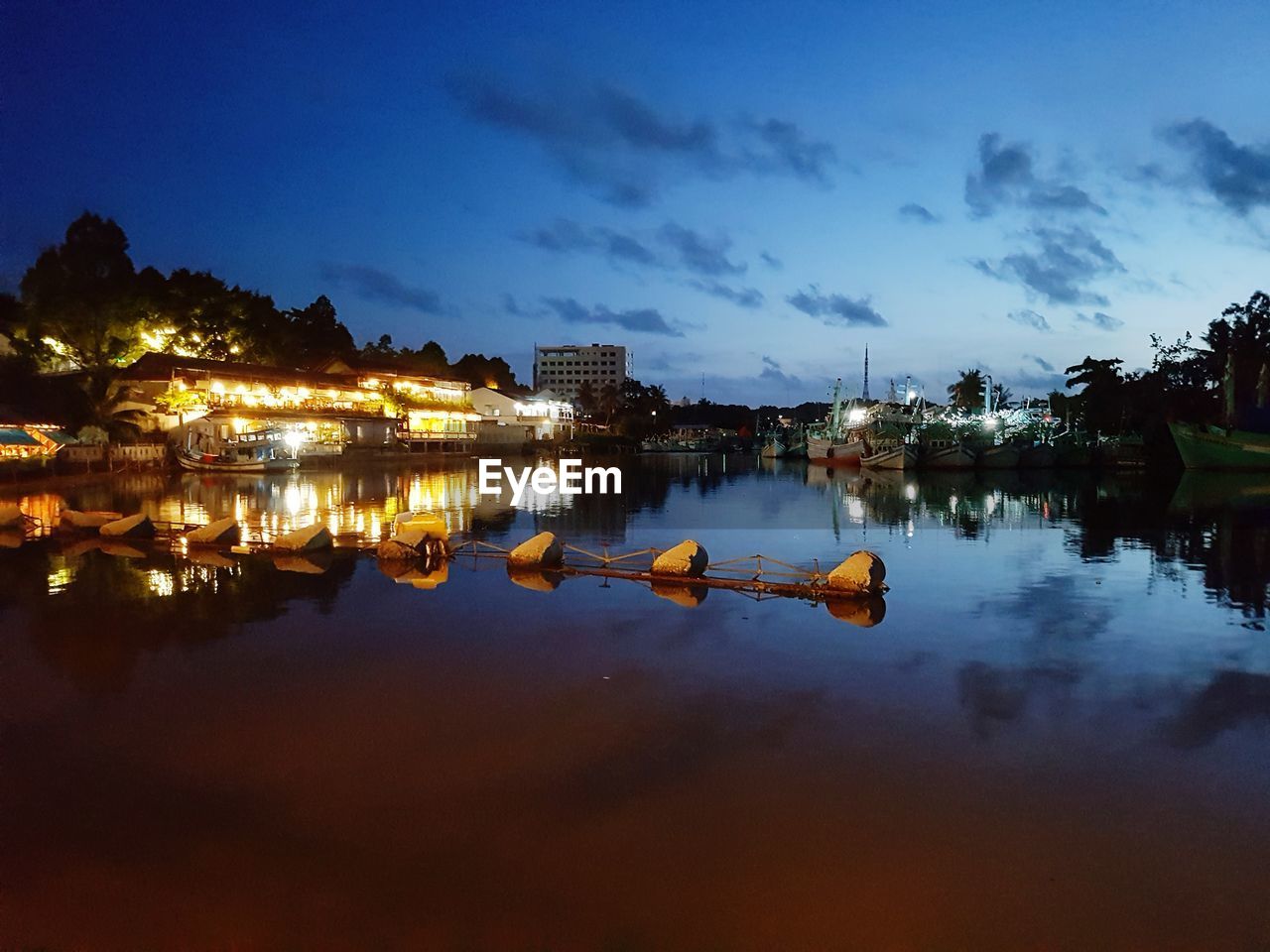 Reflection of illuminated buildings in lake against sky at night