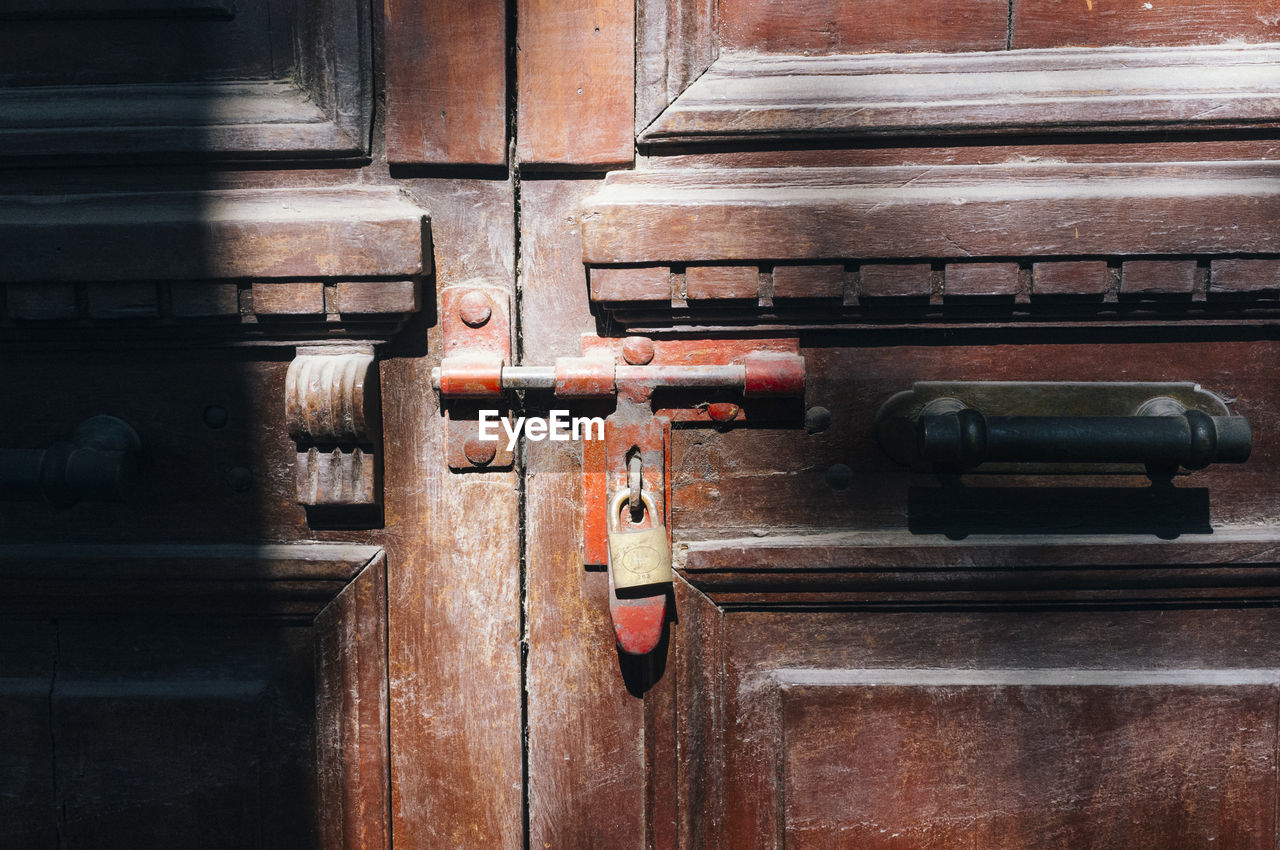 Close-up of padlock hanging on wooden door