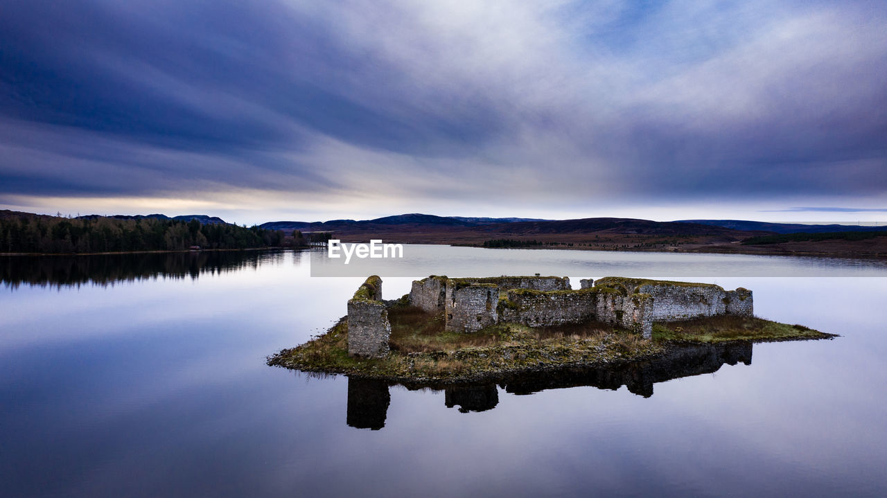 ROCK ON LAKE AGAINST SKY