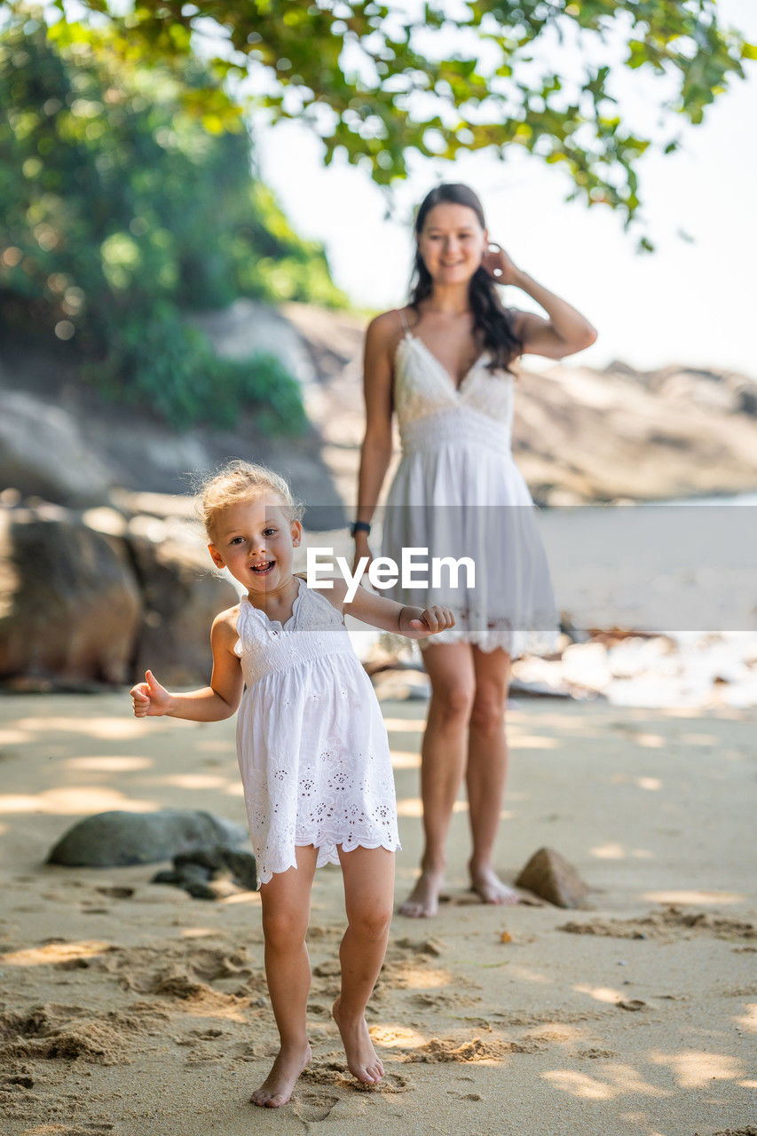 full length of mother with arms outstretched standing at beach