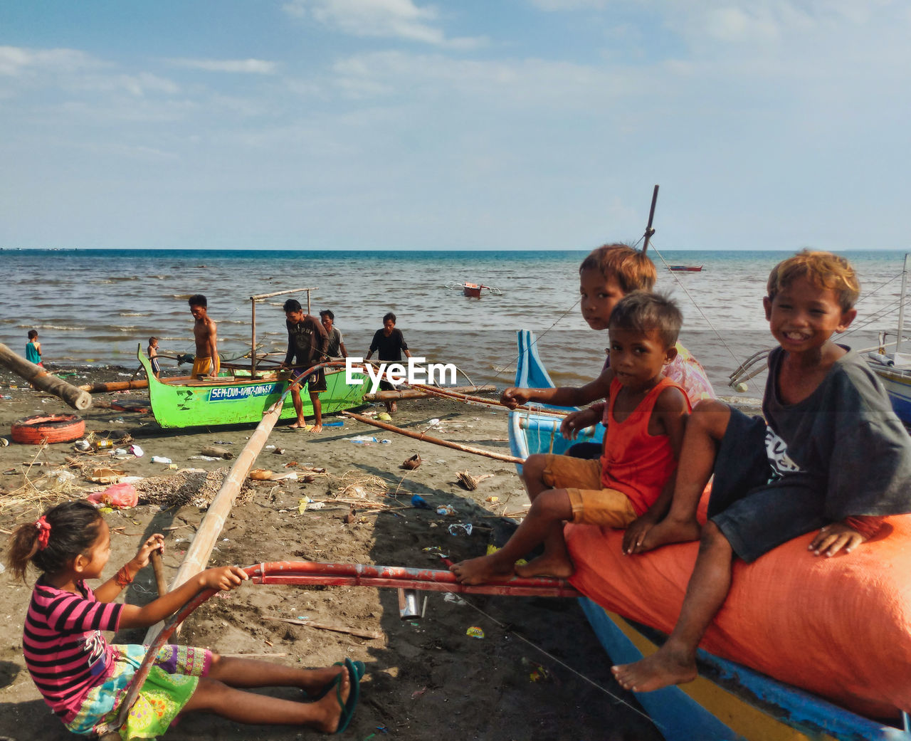 PEOPLE SITTING ON BEACH AGAINST SEA