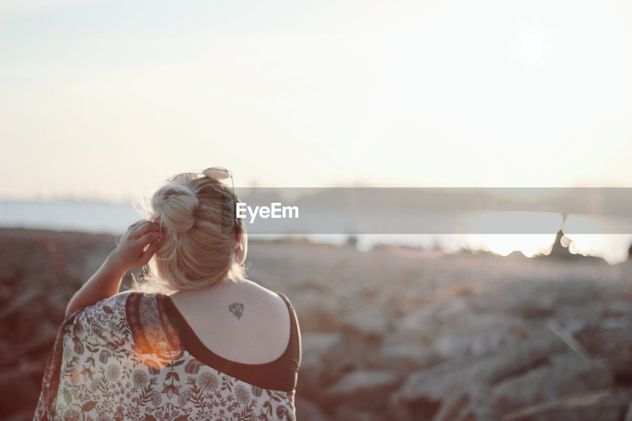 Rear view of woman standing at beach against clear sky