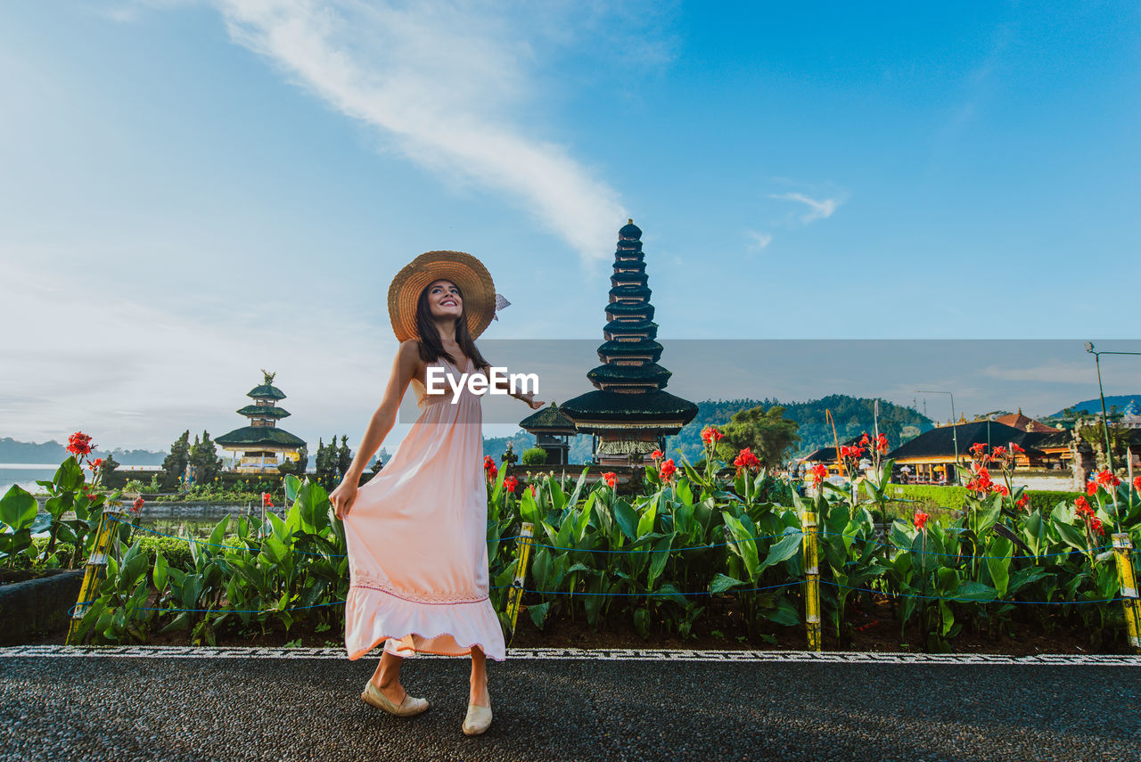 Woman standing at pura ulu danau temple against sky during sunrise