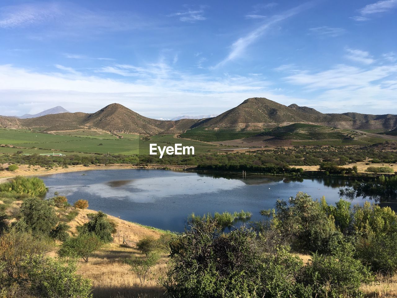 Scenic view of lake by mountains against sky