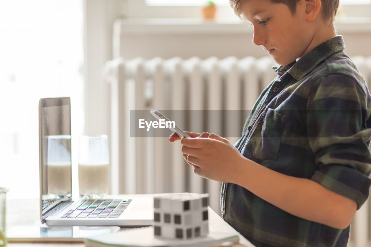 Digital native boy reading a text message on cell phone at home.