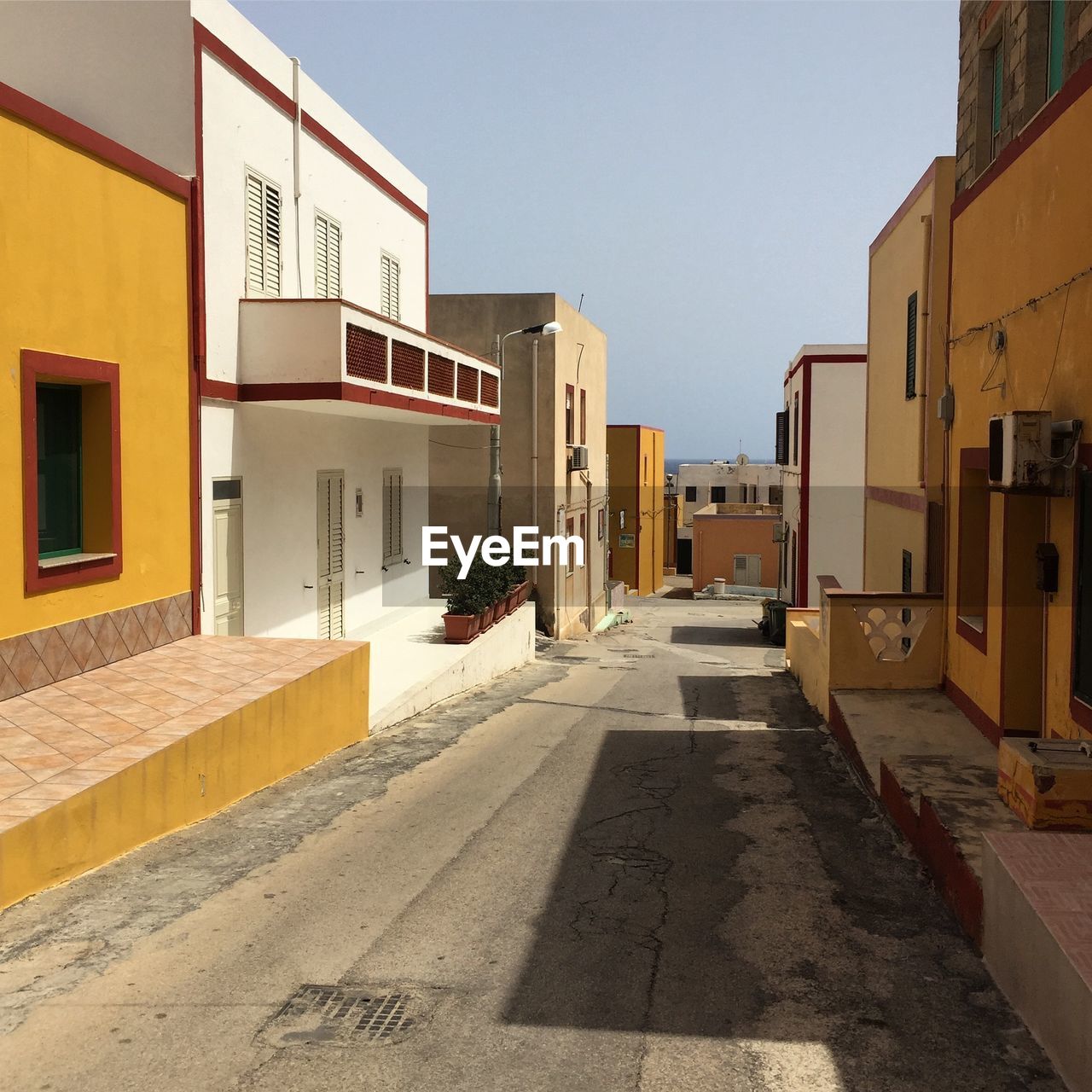 EMPTY ALLEY AMIDST BUILDINGS AGAINST SKY