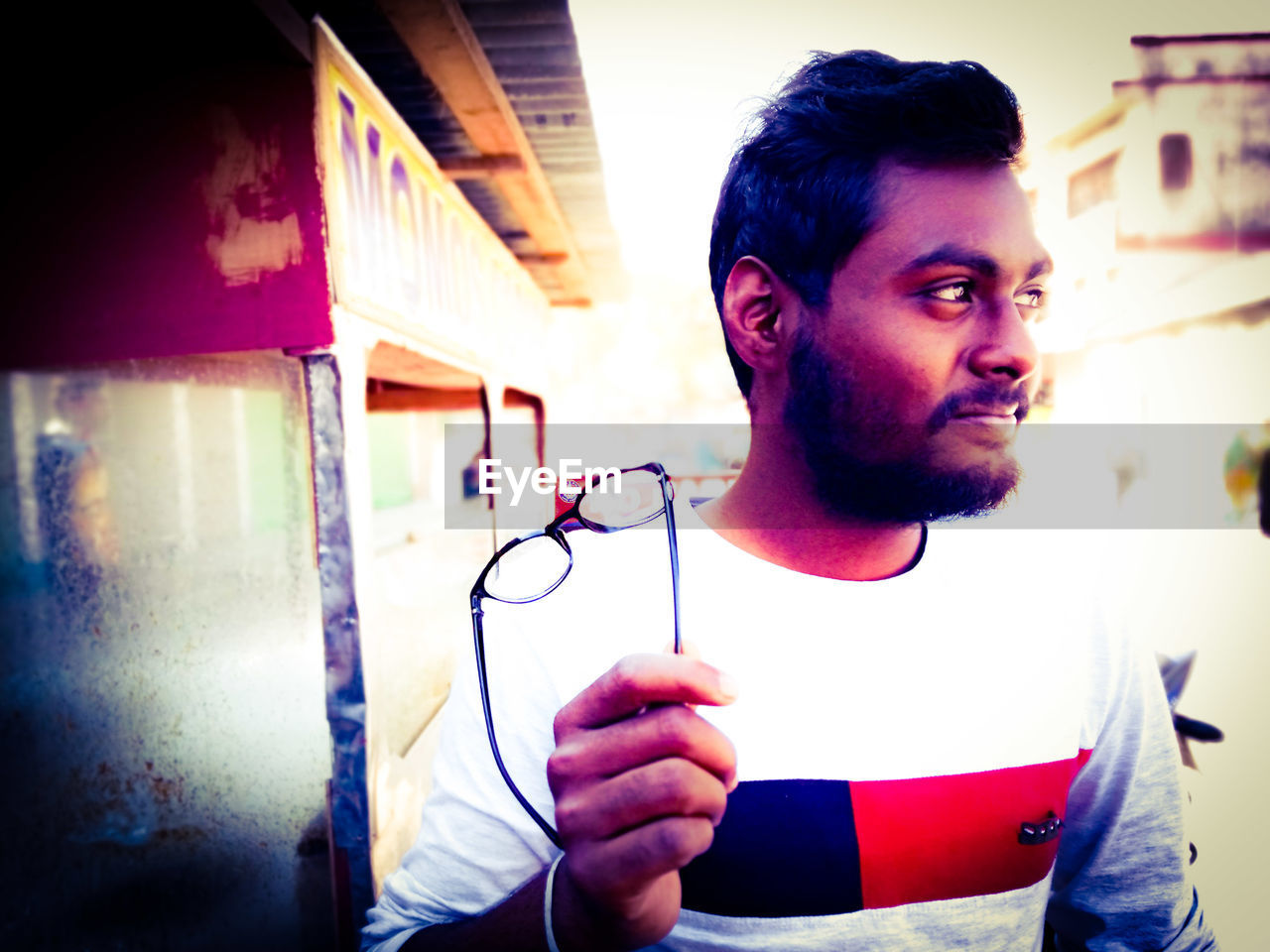 Close-up of man holding eyeglasses while looking away