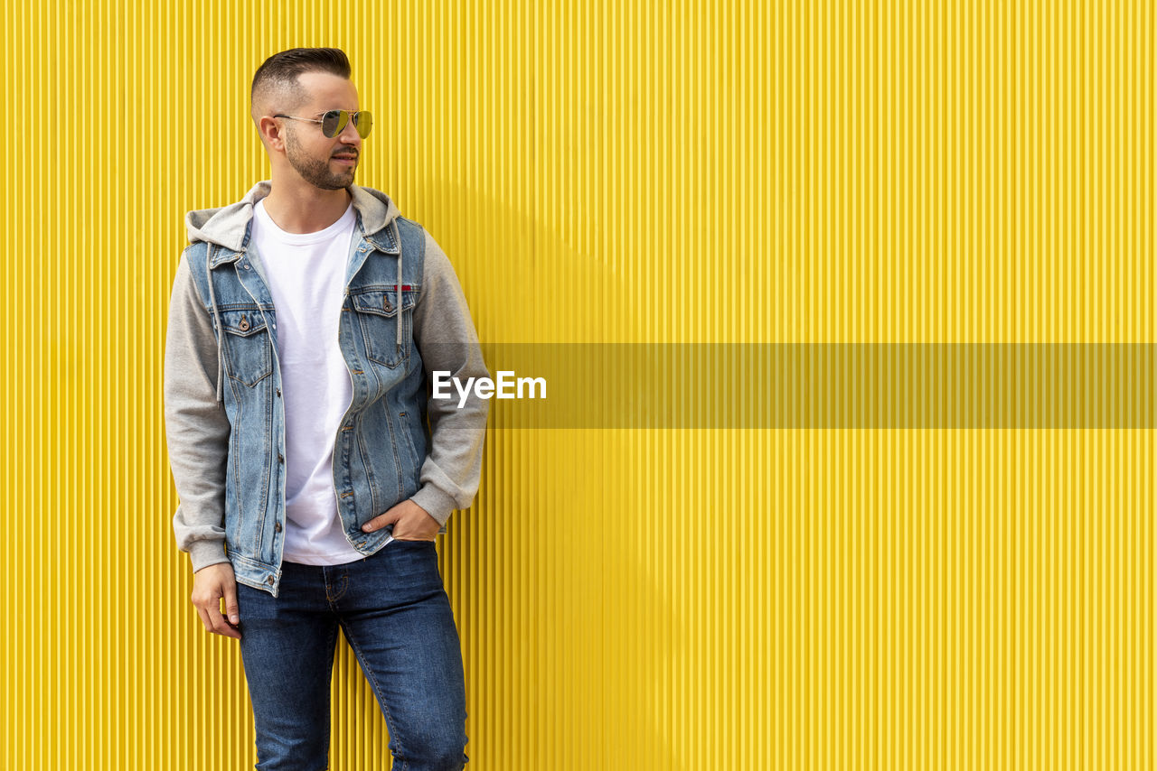 Portrait of a young cool man over yellow background.