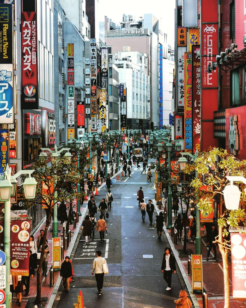 PEOPLE WALKING ON CITY STREET AMIDST BUILDINGS