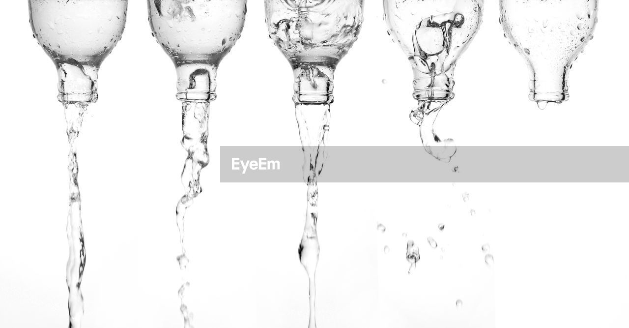 Pouring water from bottle glass isolated white background.