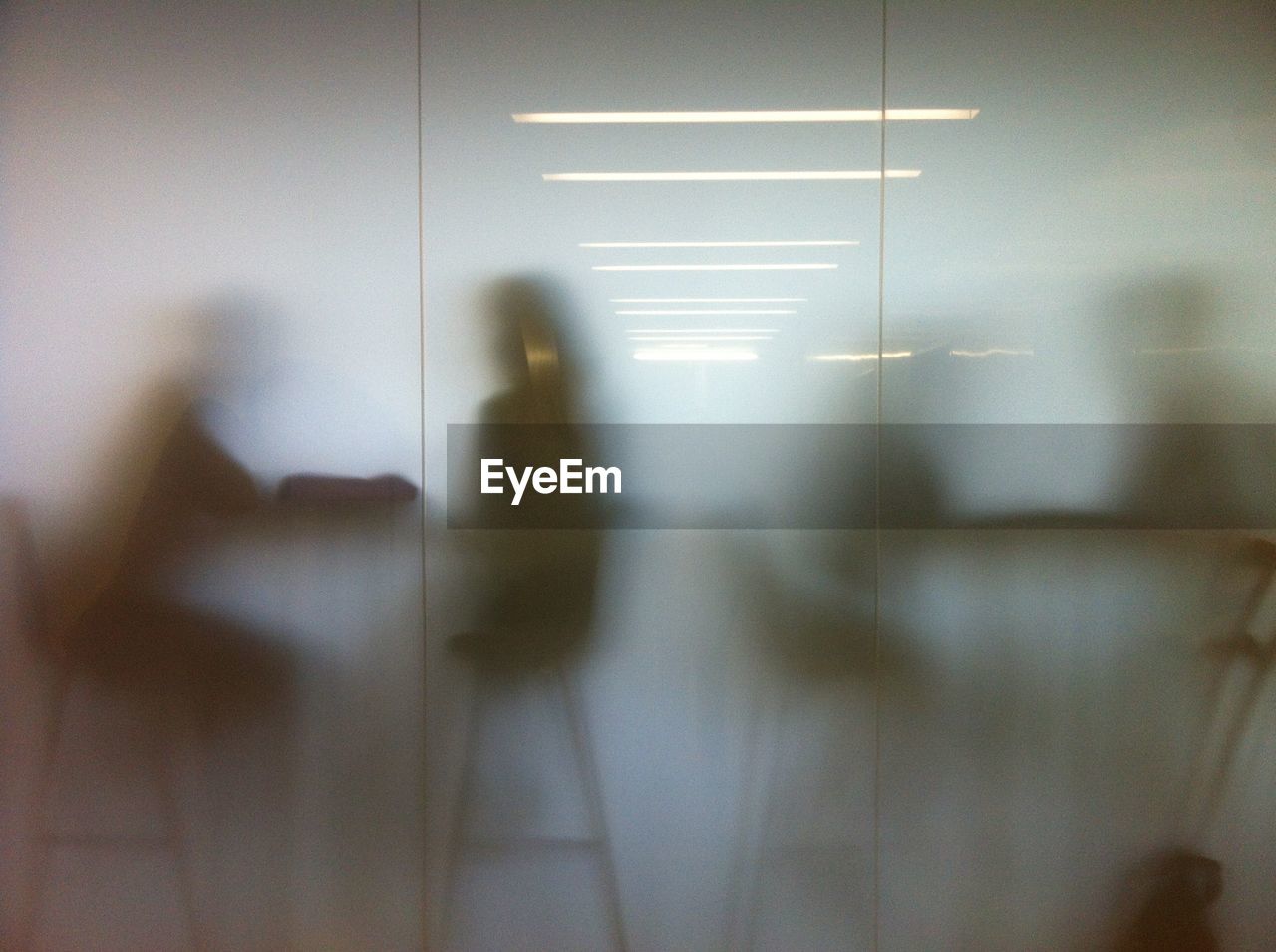 People sitting on chairs in cafe seen through glass