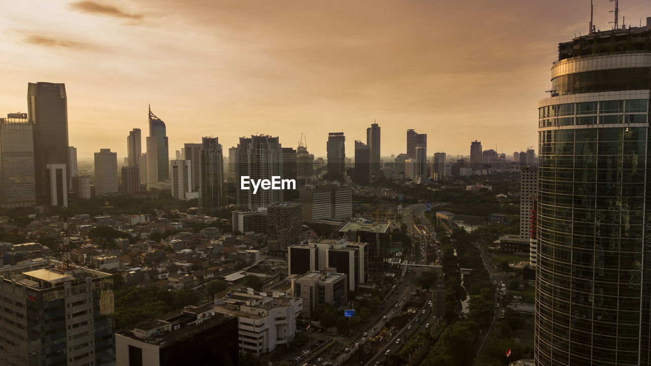 Aerial view of modern buildings in city against sky during sunset