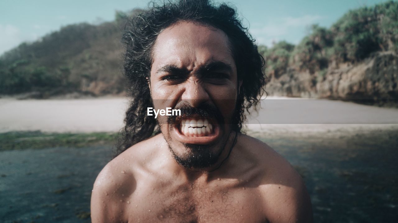 Portrait of shirtless man clenching teeth