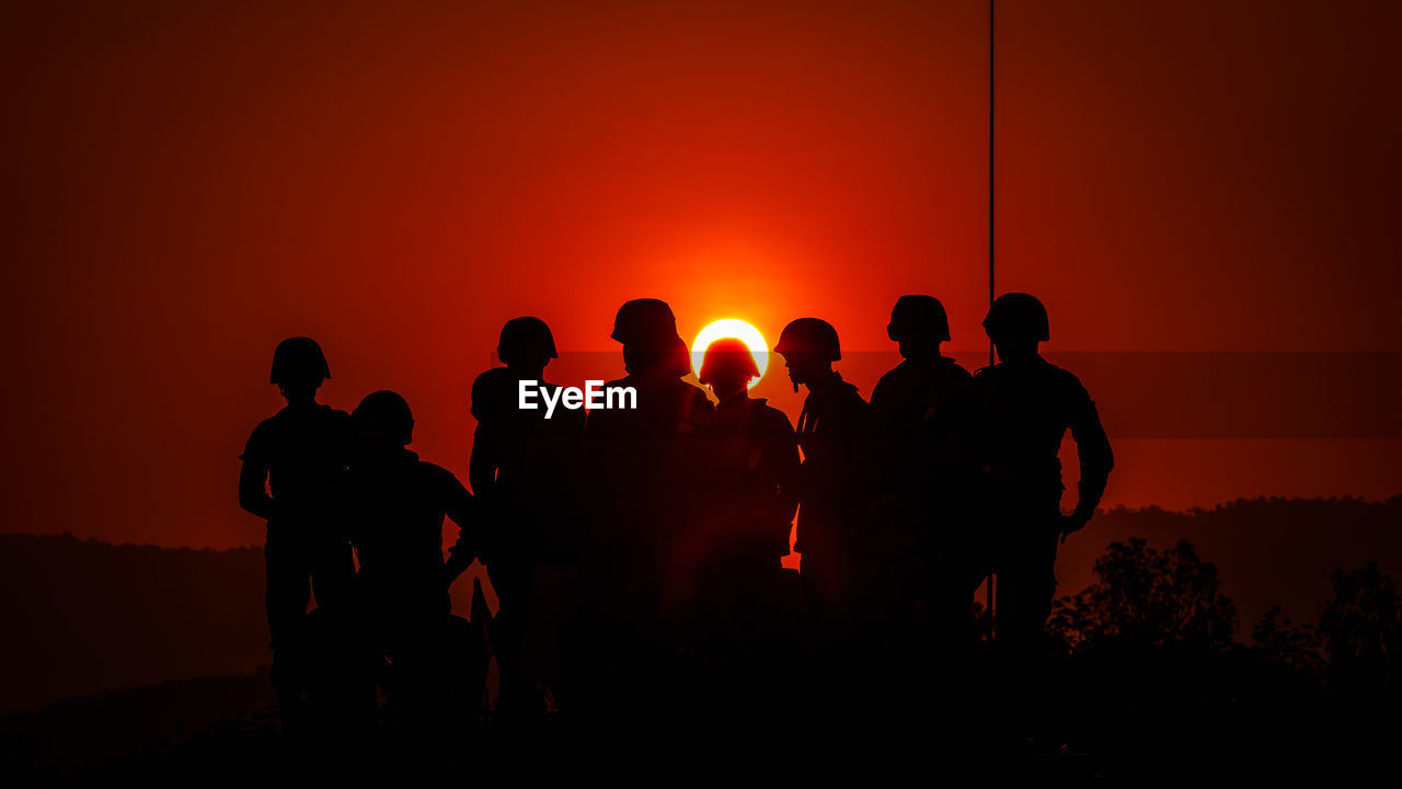 Silhouette army soldiers against sky during sunset