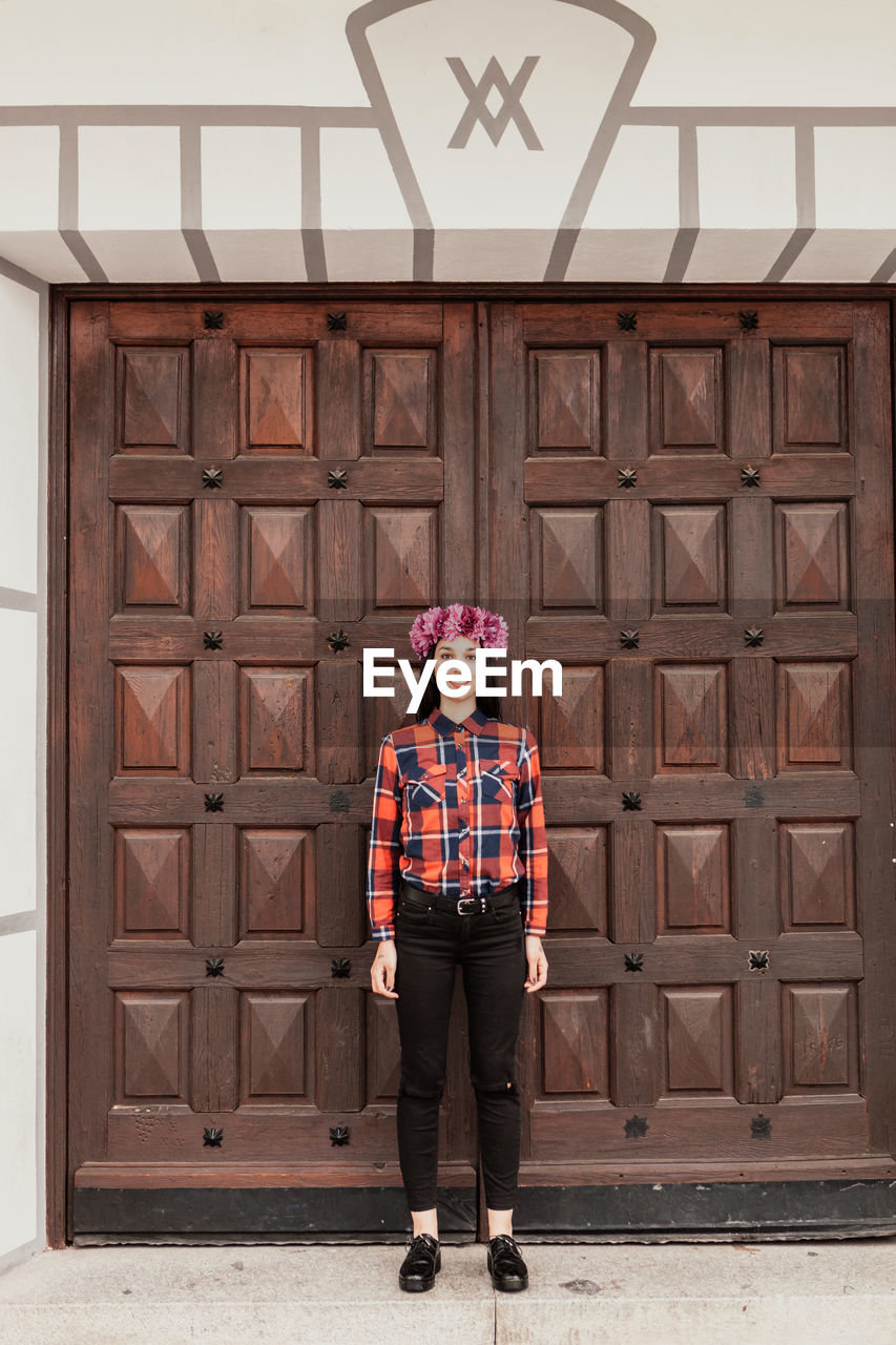 Portrait of woman standing against door