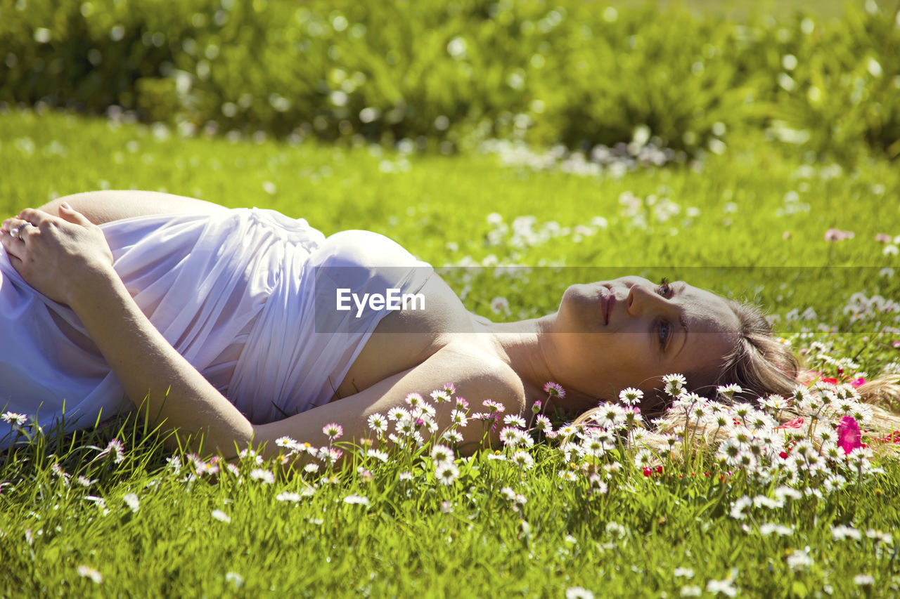 Smiling pregnant lying on grassy field
