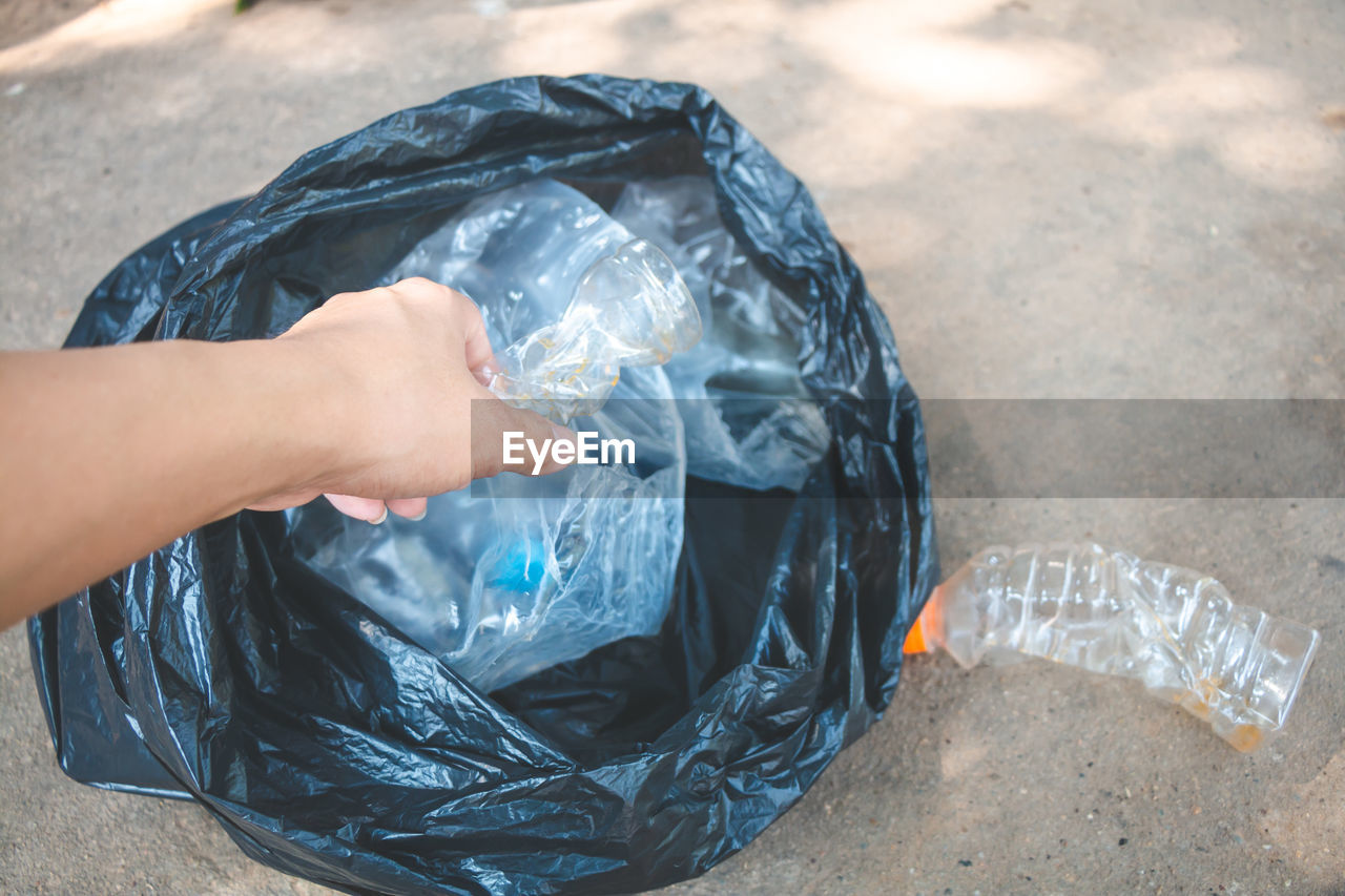 Cropped hand of woman collecting garbage in plastic bag