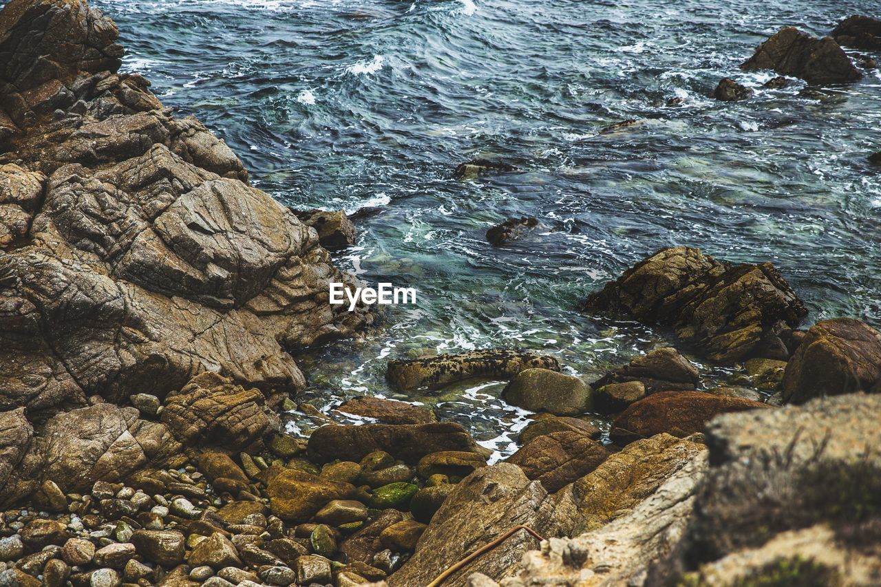 HIGH ANGLE VIEW OF ROCKS AT SEA