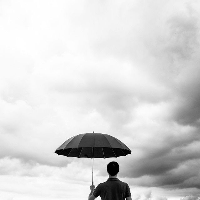REAR VIEW OF MAN STANDING AGAINST CLOUDY SKY